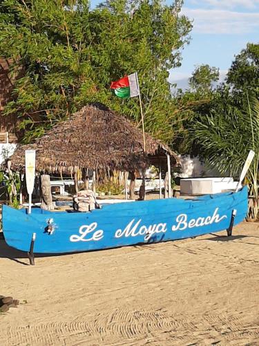 a blue boat on a beach with a flag at Le Moya Beach in Nosy Be