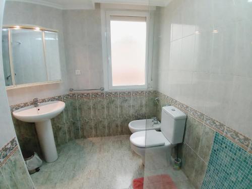 a bathroom with a toilet and a sink and a window at Laredo Ocean Port in Laredo