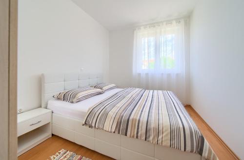 a white bedroom with a bed and a window at Apartment Anja in Krk