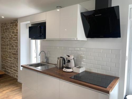 une cuisine avec des armoires blanches et un évier dans l'établissement Duplex calme et cosy, à Concarneau