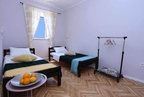 a room with two beds and a table with fruit on it at Tamaris Apartmani Igalo Centar in Herceg-Novi
