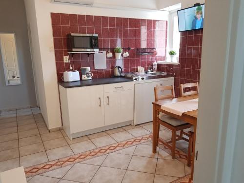 a kitchen with white cabinets and a table with a sink at Éden Villa Apartmanház in Balatonfüred
