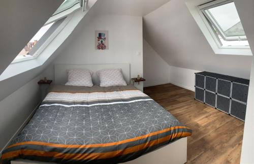 a attic bedroom with a bed and two windows at Duplex calme et cosy II in Concarneau