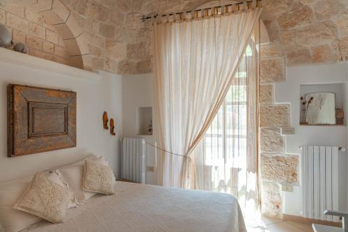 1 dormitorio con cama y ventana grande en I Sette Coni, en Cisternino