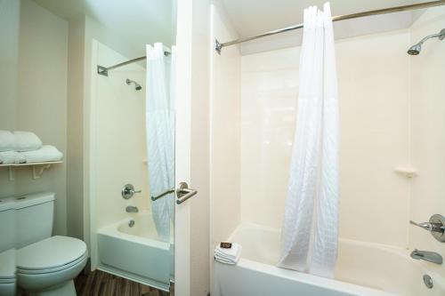 a white bathroom with a toilet and a shower at Wingate by Wyndham Brunswick GA I-95 in Brunswick