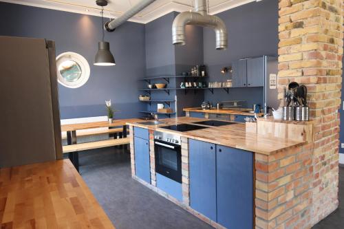 a kitchen with blue cabinets and a brick wall at Blue Doors Hostel KTV in Rostock