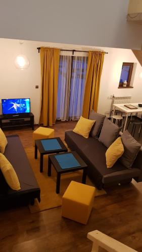 a living room with a couch and a tv at Osada nad Potokiem in Szczyrk
