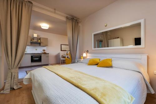 1 dormitorio con 1 cama blanca grande con almohadas amarillas en Apartments Javor, en Rovinj