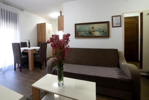 sala de estar con sofá y mesa con flores en "Mini Hotel Vienna" Apartments en Vrnjačka Banja