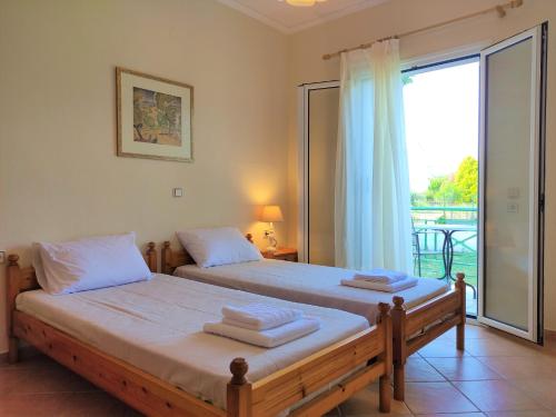 a bedroom with two beds and a large window at Oikia Dinachris in Agios Georgios