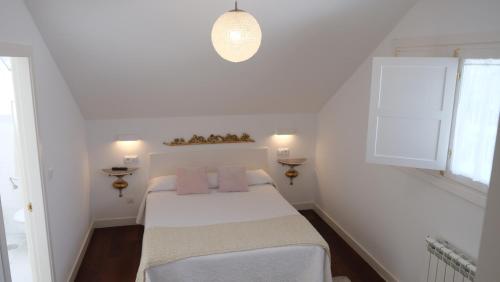 a white bedroom with a bed with pink pillows at HOTEL LA CASA DE LAS CAMELIAS in Busto