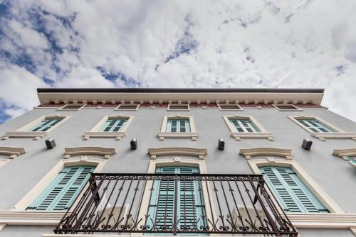 a tall white building with green shuttered windows at Gardone Palace Hotel in Gardone Riviera