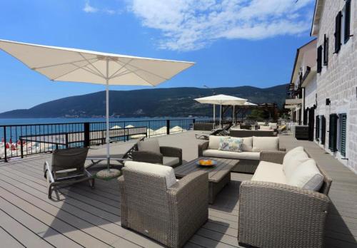 a patio with couches and a table and an umbrella at Tamaris Apartmani in Herceg-Novi