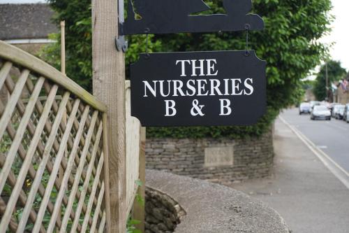 The Nurseries Bed and Breakfast Fairford في فيرفورد: لافته مكتوب عليها حضانة الاطفال و ب على سياج