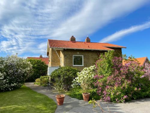 a brick house with a red roof and some bushes at HEMMET Simrishamns vandrarhem och B&B in Simrishamn