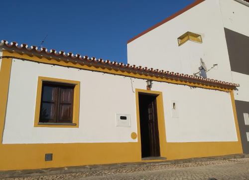 a white and yellow building with a black door at Casa da Avó Velhinha in Telheiro