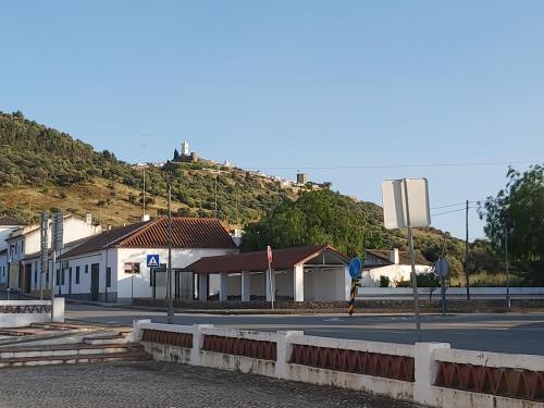 a street with buildings and a hill in the background at Casa da Avó Velhinha in Telheiro