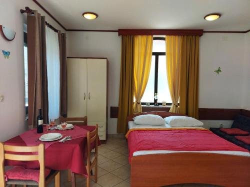 a hotel room with two beds and a table and a table and chairs at P&Z Apartments in Rab