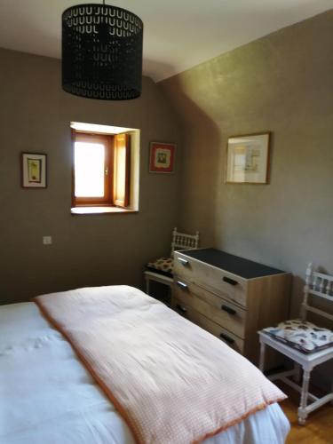 une chambre avec un lit, une commode et une fenêtre dans l'établissement La grange, à Kervignac