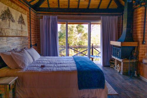 a bedroom with a bed and a large window at Chalés Descanso na Serra in Monte Verde