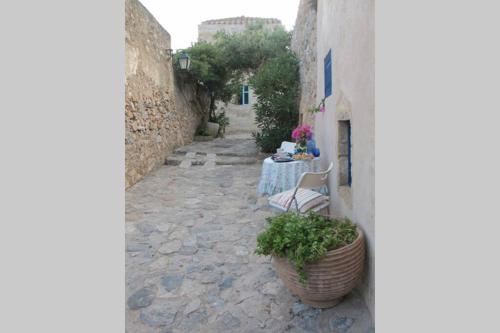 a stone alley with a table and a plant at Blue Door (in the castle of Monembasia) in Monemvasia
