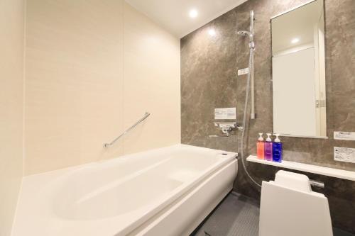 a bathroom with a white tub and a shower at Richmond Hotel Morioka Ekimae in Morioka