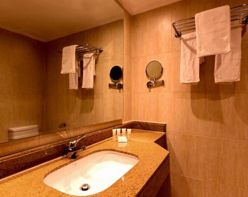 a bathroom with a sink and a mirror and towels at The Grand Plaza Hotel Smouha in Alexandria