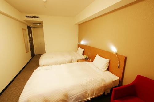 a hotel room with two beds and a desk at Hotel Century Art in Fukuoka