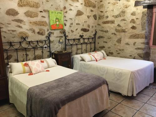 two beds in a room with stone walls at Casa Rural La Antigua Tahona in Candelario