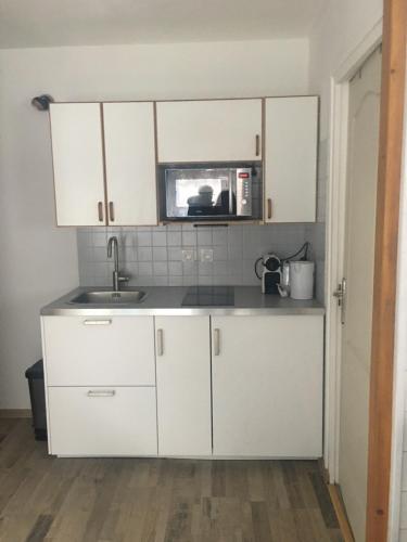 a kitchen with white cabinets and a microwave at OUTA Chamonix centre in Chamonix