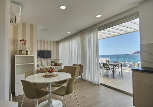 uma sala de estar com mesa e cadeiras e uma sala de estar em Malibú Canteras Ático 23 Vista Mar - Seaview Penthouse em Las Palmas de Gran Canaria