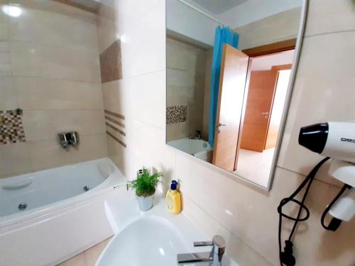 a bathroom with a sink and a tub and a mirror at Apartamente Sara Holiday in Mamaia
