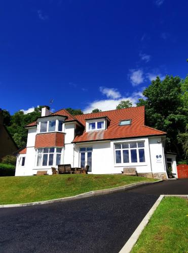 a white house with a red roof on a street at The Knowe Guest House in Callander
