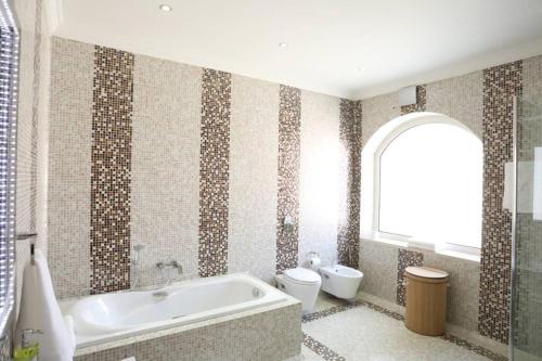 ein Bad mit einer Badewanne und einem WC in der Unterkunft Villa Sea Breeze in Sowayma