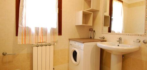 a bathroom with a washing machine and a sink at Ville Timoniere 6B in Isola Albarella