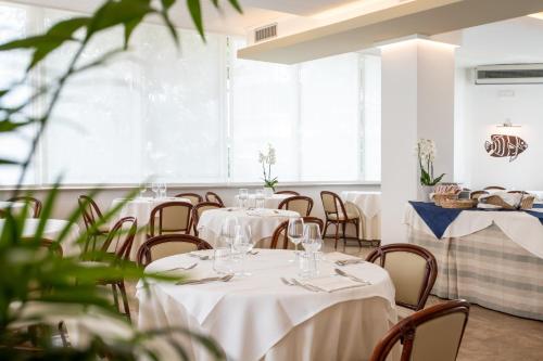 a dining room with white tables and chairs at Hotel Mirafiori in Lido di Jesolo