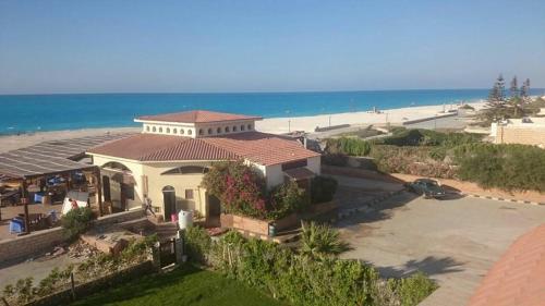 une maison sur la plage avec l'océan derrière elle dans l'établissement Roof 5 OR 6 3 Bedrooms sea view 114Green Beach, à El Alamein