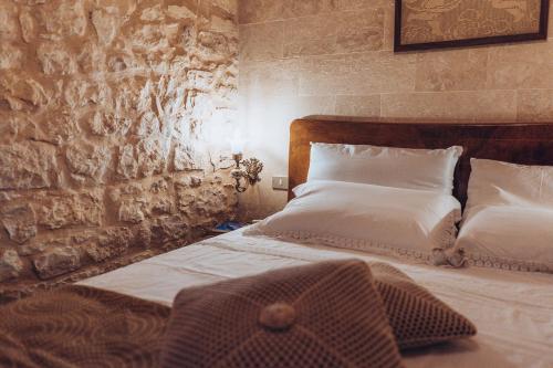 a bedroom with two beds and a stone wall at Le Cacinare in Modica