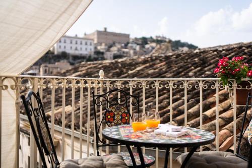a table with two glasses of orange juice on a balcony at Le Cacinare in Modica