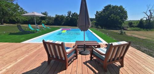 a deck with two chairs and an umbrella next to a pool at Domaine de Gaïa, Piscine, Pétanque, Ping-pong, proche Saint Emilion in Guillac