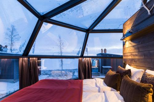 - une chambre avec une grande fenêtre en verre et un lit dans l'établissement Ranua Resort Arctic Igloos, à Ranua