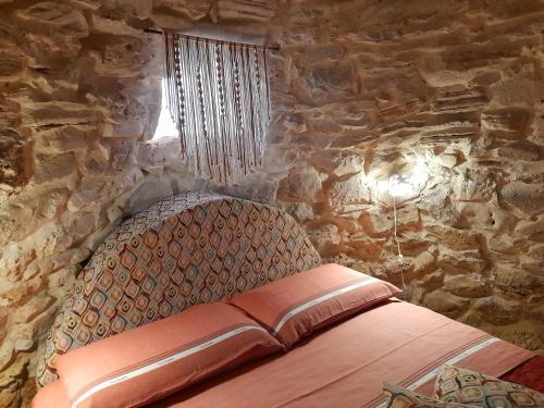 ein Schlafzimmer mit einer Steinmauer und einem Bett darin in der Unterkunft Trullo "Il fico d'india" in Alliste