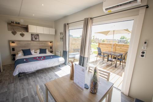 a bedroom with a bed and a patio with a table at M&V Resort Camping in Langrune-sur-Mer
