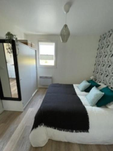 une chambre avec un grand lit et un miroir dans l'établissement A 300m de la plage, appartement moderne et cosy, à Merville-Franceville-Plage