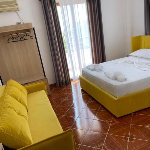 a bedroom with a bed and two yellow chairs at Villa Gaudium in Vlorë
