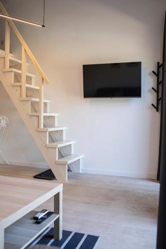 a living room with stairs and a flat screen tv at Alyvų Namai Nida in Nida