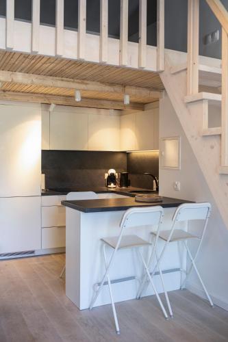 a kitchen with two white chairs at a counter at Alyvų Namai Nida in Nida
