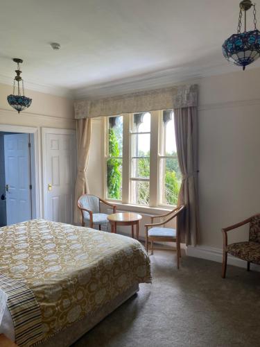 a bedroom with a bed and a table and windows at Farnley Tower Guesthouse in Durham