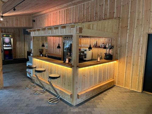 a bar with stools in a room with wooden walls at Enderupskov Camping & Cottages in Gram