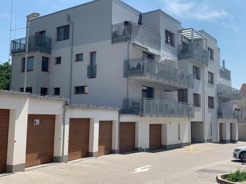 un edificio bianco con due porte garage e un parcheggio di Kellerův mlýn - Apartmán s vlastní garáží, Znojmo centrum a Znojmo